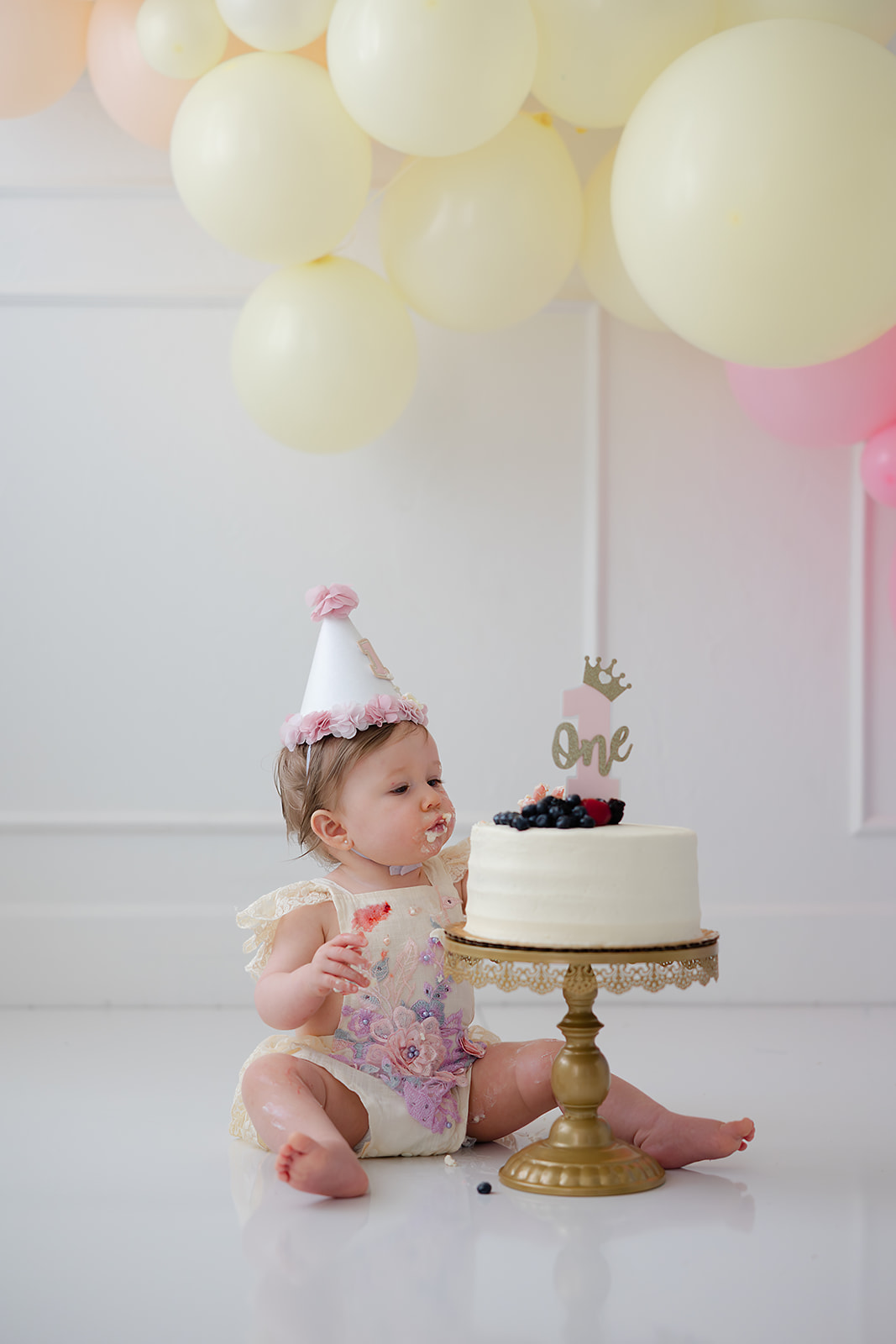 Baby celebrating a first birthday during a cake smash portrait session